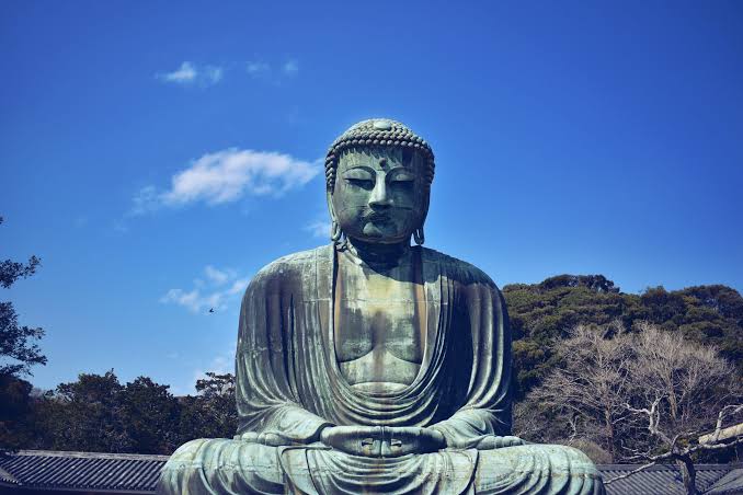 A large seated Buddha statue under a clear sky